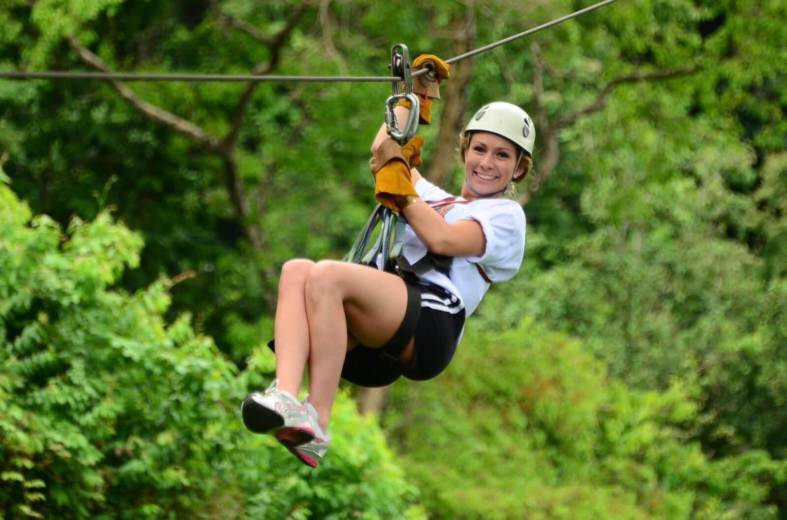 Smiling guest enjoying a canopy zipline ride over the jungle in Jaco.