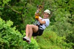 Smiling guest enjoying a canopy zipline ride over the jungle in Jaco.