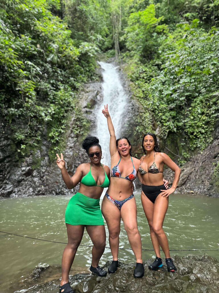 Jaco Waterfall Experience Women posing in front of a waterfall during the Jaco Waterfall Tour