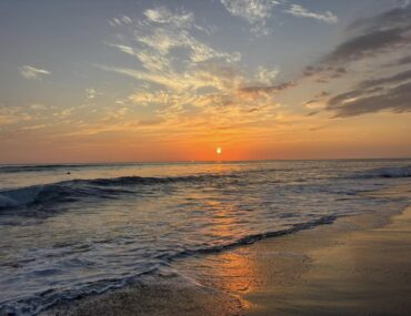 Sunset over Jaco Beach, Costa Rica, with waves along the Pacific coast