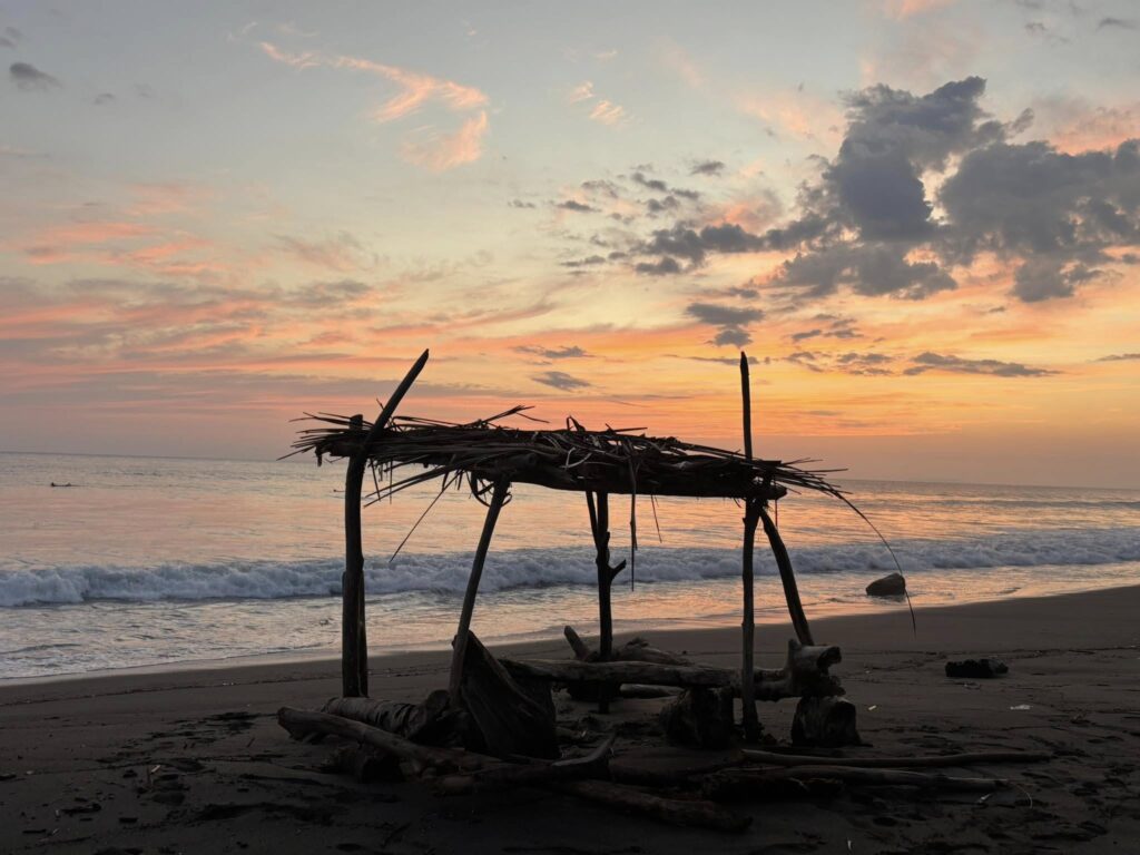 Jaco Beach Costa Rica Sunset View Sunset over Jaco Beach, Costa Rica, with driftwood shelter on the shore