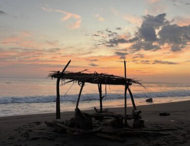 Sunset over Jaco Beach, Costa Rica, with driftwood shelter on the shore